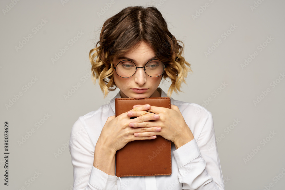 Business woman with notepad and glasses on a light background hairstyle success emotions Business woman with notepad and glasses on a light background hairstyle success emotions