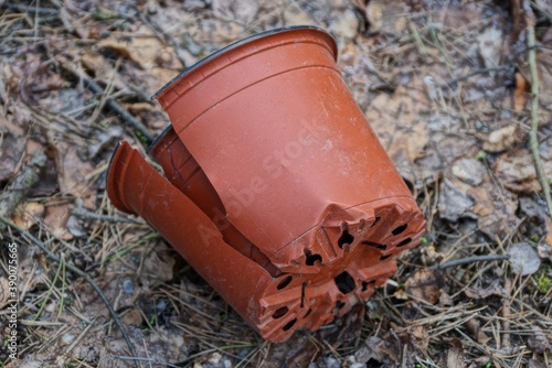 Fototapeta garbage from one brown broken plastic flowerpot with a crack lies on the ground