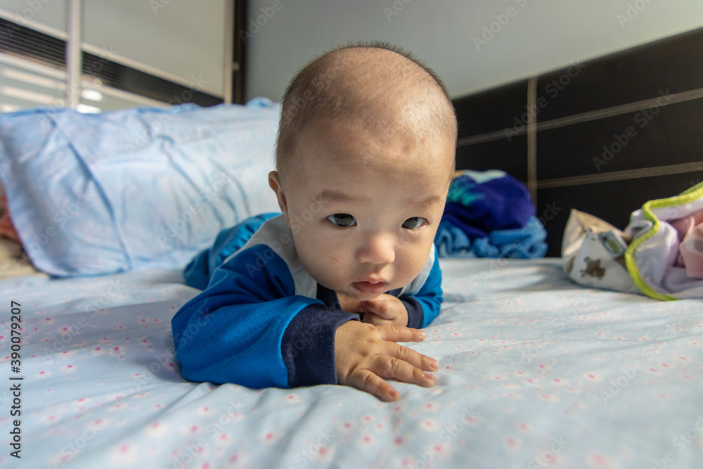 Adorable baby boy during tummy time on bed. Newborn child relaxing in bed Adorable baby boy during tummy time on bed. Newborn child relaxing in bed