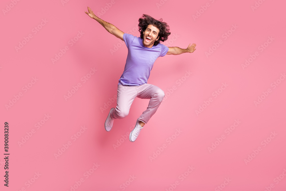 Full size photo of positive bristled happy young man make hands plane wings jump fly wear pink pants isolated on shine pink color background
