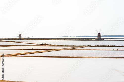 Landscape view of the salt Pans of Trapani in Sicily with colorful waters, white salt piles and red wind mill