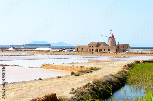 Landscape view of the salt Pans of Trapani in Sicily with colorful waters, white salt piles and red wind mill