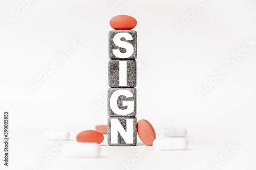 a group of white and red pills and cubes with the word sign on them, white background. Concept carehealth, treatment, therapy. photo