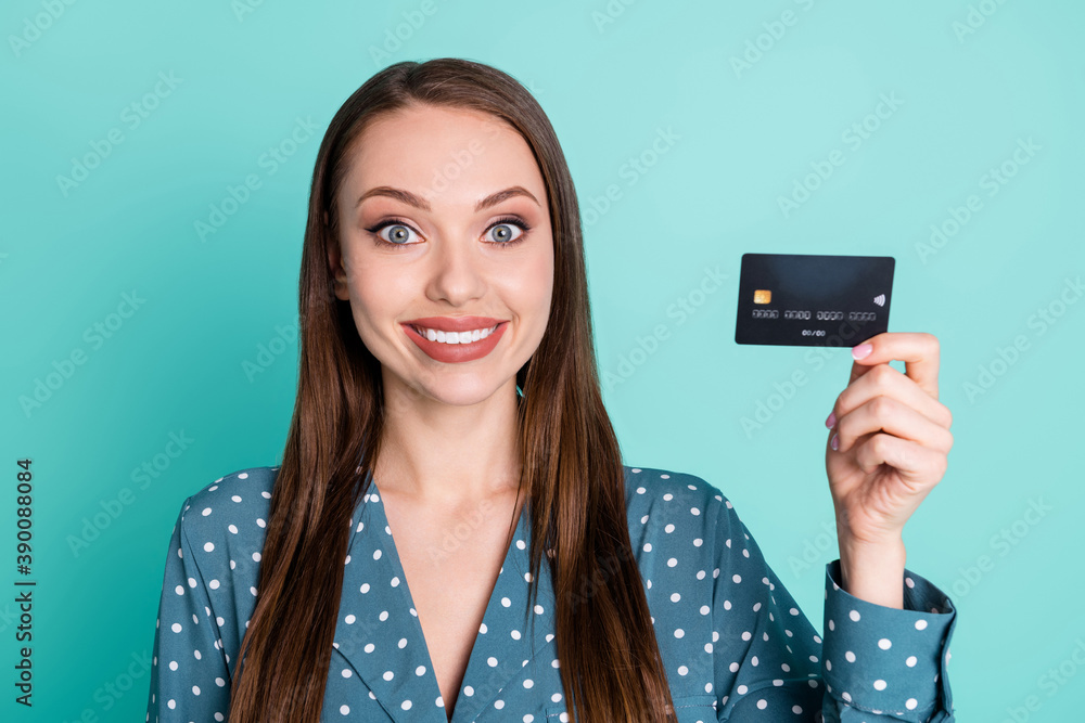 Portrait of positive cheerful girl hold credit card wear blue polka-dot blouse isolated over turquoise color background Portrait of positive cheerful girl hold credit card wear blue polka-dot blouse isolated over turquoise color background