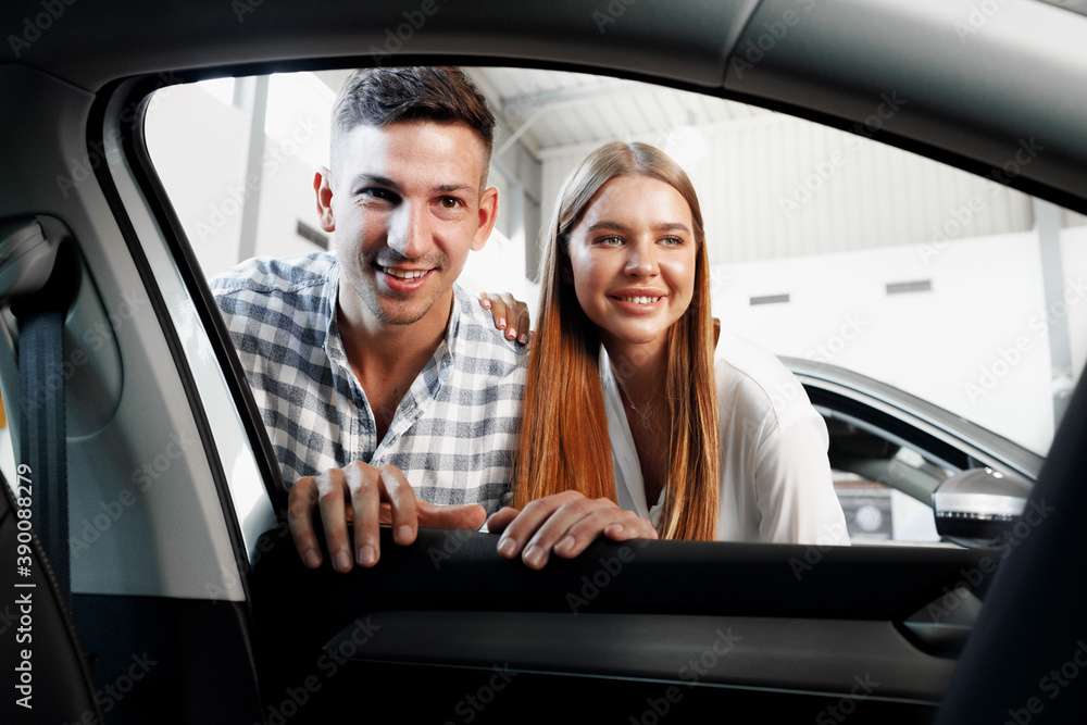 Young couple choosing their new car in a car shop