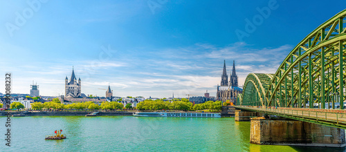 Panorama of Cologne city historical centre with Cologne Cathedral of Saint Peter, Great Saint Martin Roman Catholic Church buildings and Hohenzollern Bridge across Rhine river. Cologne panoramic view