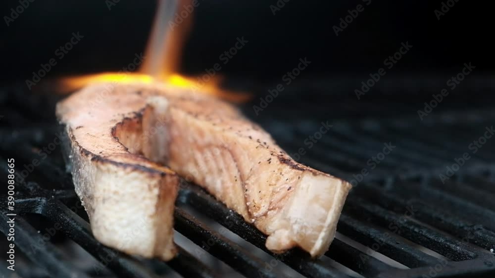 Salmon steak is grilled on barbecue. Seafood on grill. cook burns piece ...