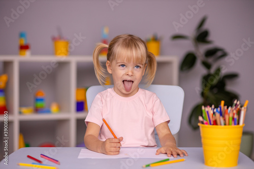 Cute little child girl writing with pencils in day care center