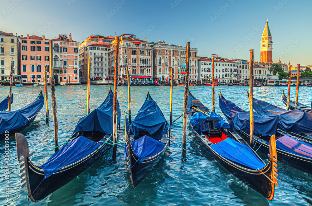 Gondolas moored in water of Grand Canal waterway in Venice. Baroque style colorful buildings along Canal Grande and bell tower Campanile di San Marco. Typical Venice cityscape, Veneto Region, Italy