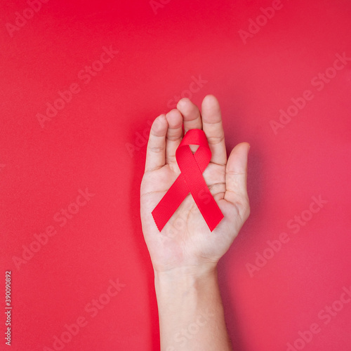Hand holding Red Ribbon for supporting people living and illness. Healthcare and safe sex concept. December World Aids Day and multiple myeloma Cancer Awareness month