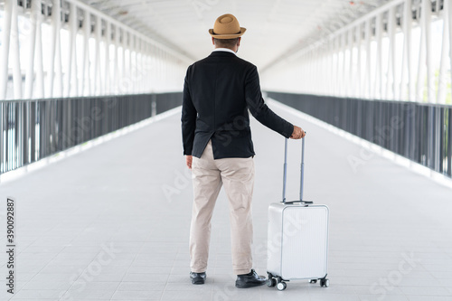Wallpaper Mural Casual businessman travel with trolley bag walking in the airport terminal. Young man wearing mask arrive to airport. Safety travel concept. Torontodigital.ca
