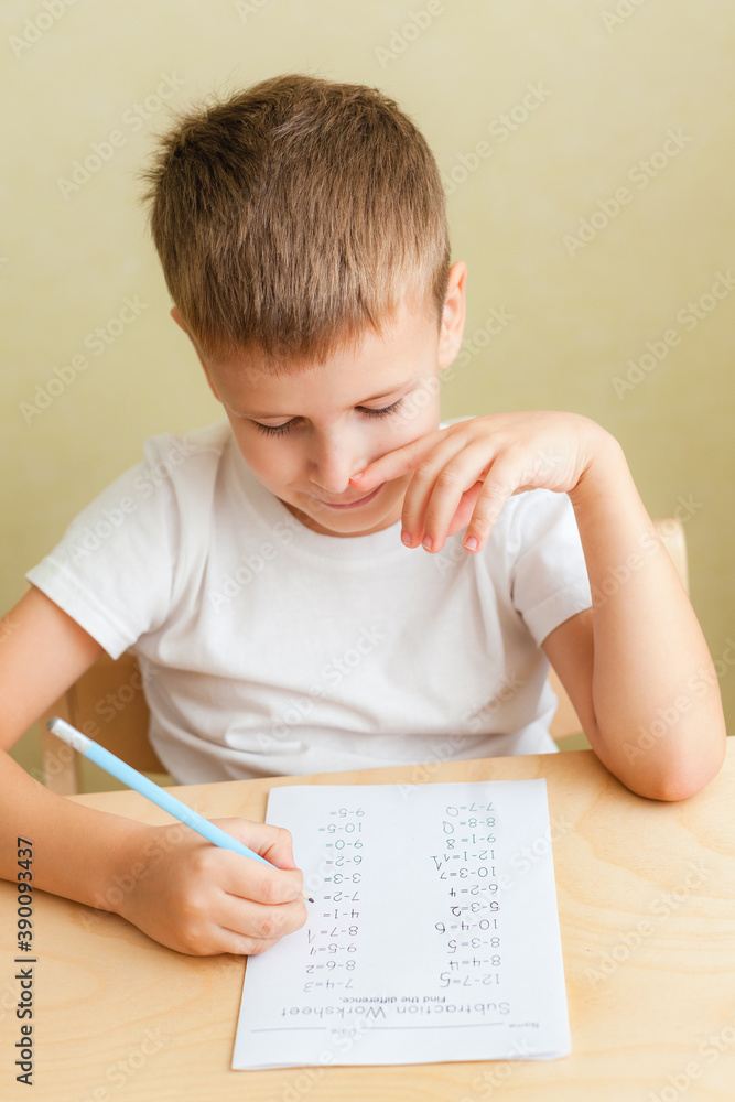 Close up portrait of cute boy learning at home. 7 years old child doing maths lessons sitting at desk in his room. Close up portrait of cute boy learning at home. 7 years old child doing maths lessons sitting at desk in his room.