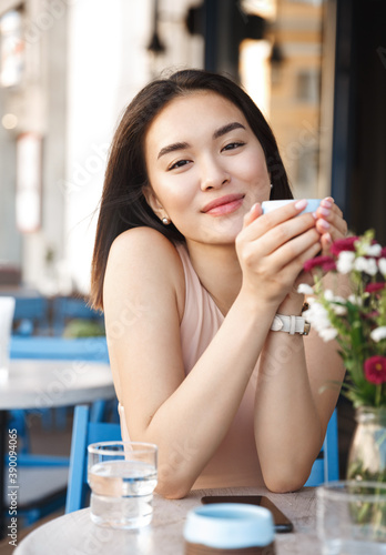 Portrait of happy young business woman with mug in hands drinking coffee in the morning at restaurant