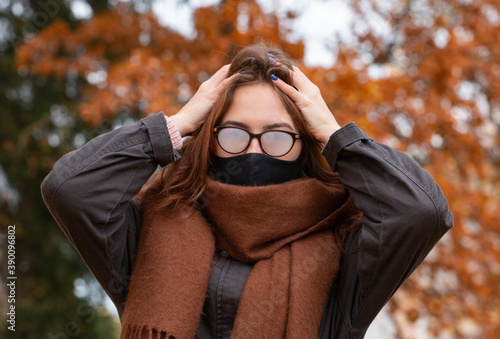 Foto The woman clutched her head, wears a black mask due to the pandemic, but her glasses are fogged up