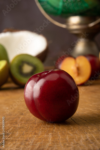 Plum in the foreground over rustic wood and fruits in the background  selective focus.