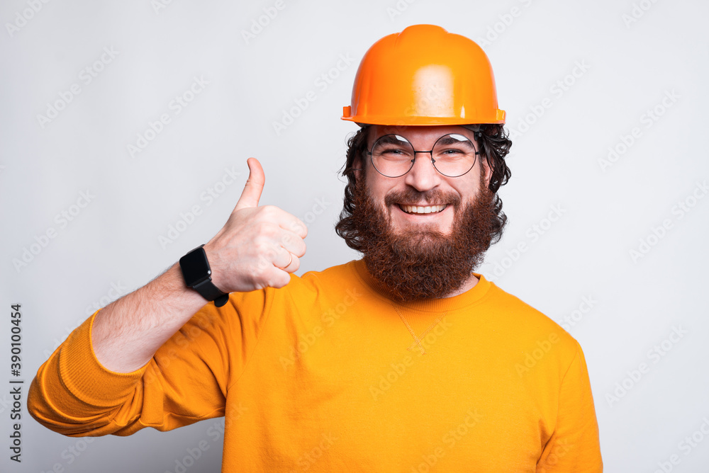 Portrait of smiling young architect showing thumb up and wearing helmet. Portrait of smiling young architect showing thumb up and wearing helmet.