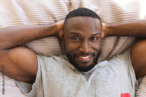 Portrait of  african american man smiling while lying with hands behind his head at home photo