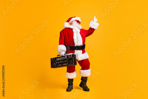 Full size photo of crazy santa claus with grey beard listen boom box dance x-mas christmas party wear headwear cap sunglass boots isolated over bright shine color background