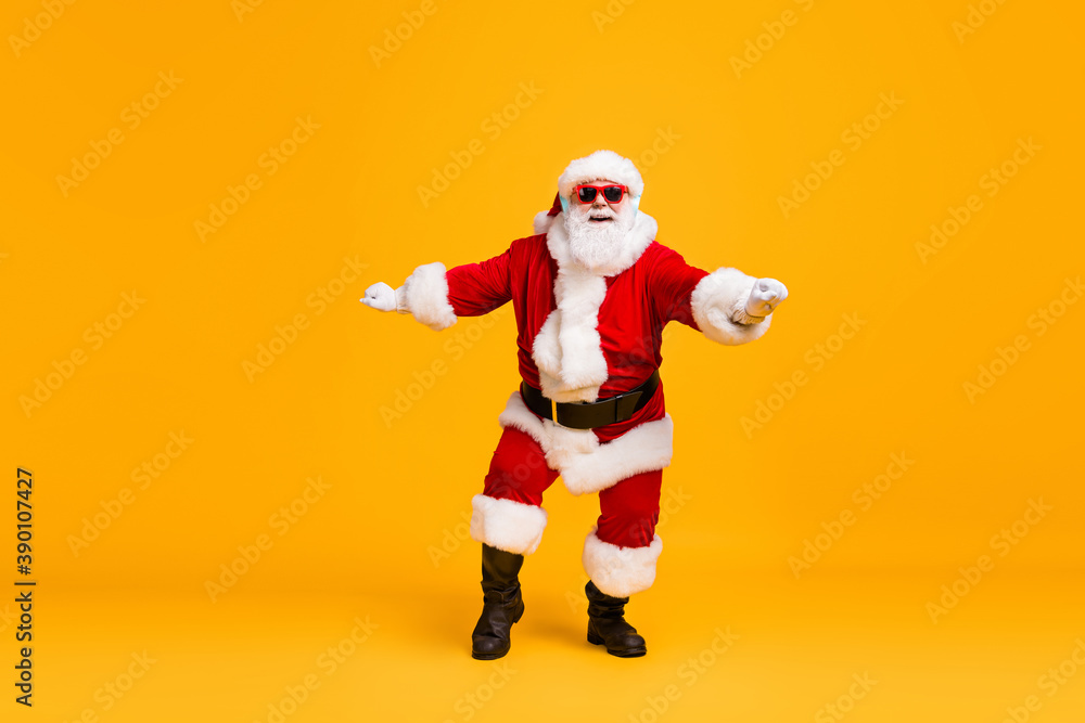 Full size photo of funky santa claus with grey beard listen x-mas christmas music song headset dance wear sunglass headwear cap isolated over bright shine color background Full size photo of funky santa claus with grey beard listen x-mas christmas music song headset dance wear sunglass headwear cap isolated over bright shine color background