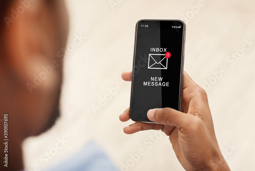 African Man Using Smartphone Reading Email Message Indoors, Cropped