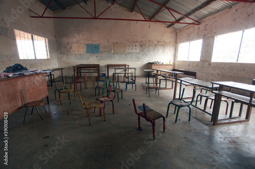 wide angle horizontal photography of  an African school classroom with white walls, bright windows and many empty wooden and metal chairs, in the Gambia . Africa with natural light © agarianna