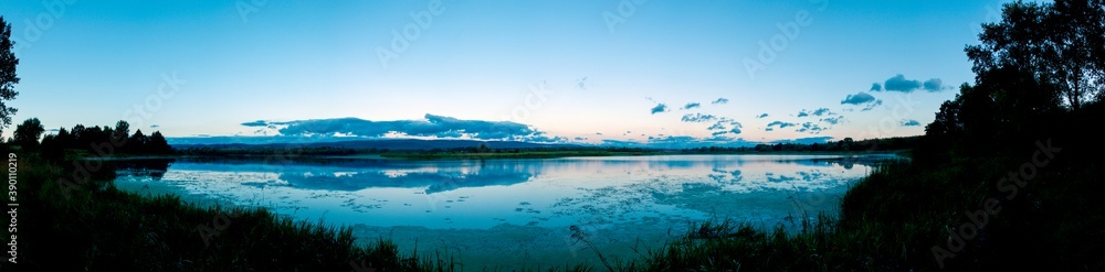 fishing pole with beautiful lake, mountains, forest and steel sky background. Fishing tool and sport concept