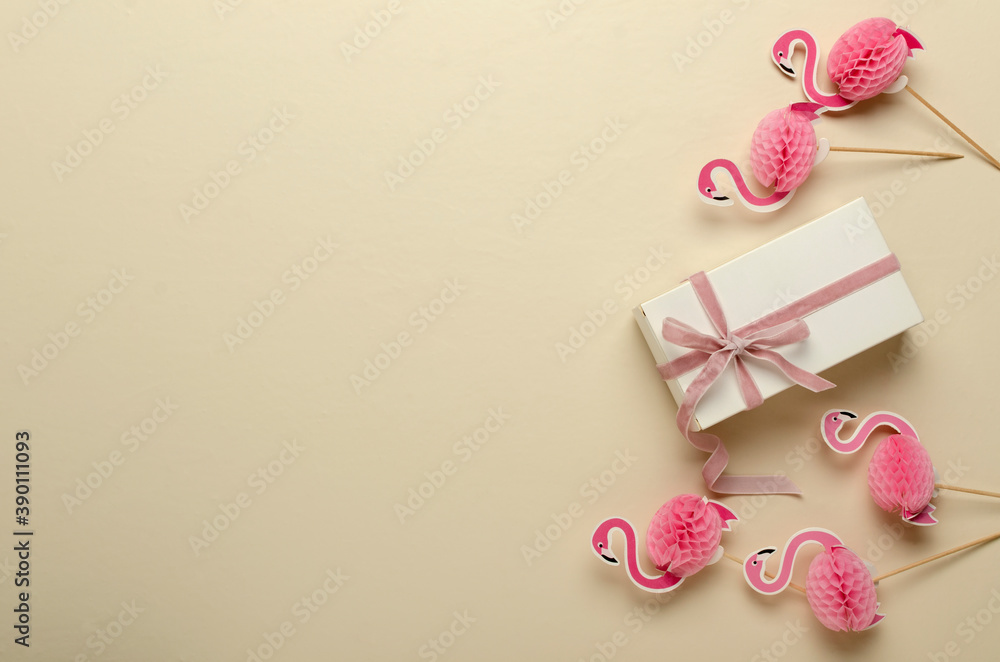 Top view of gift box and pink ribbon, decorative flamingos on the bright surface.Empty space Top view of gift box and pink ribbon, decorative flamingos on the bright surface.Empty space