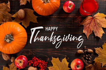 Thanksgiving greetings. Dry yellow leaves, pumpkins, berries, nuts and frame on a wooden background, top view. Kaligraphic capital inscription.