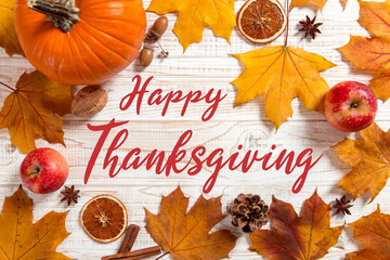 Thanksgiving greetings. Dry yellow leaves, pumpkins, berries and apples on a white background, top view. Kaligraphic capital inscription.