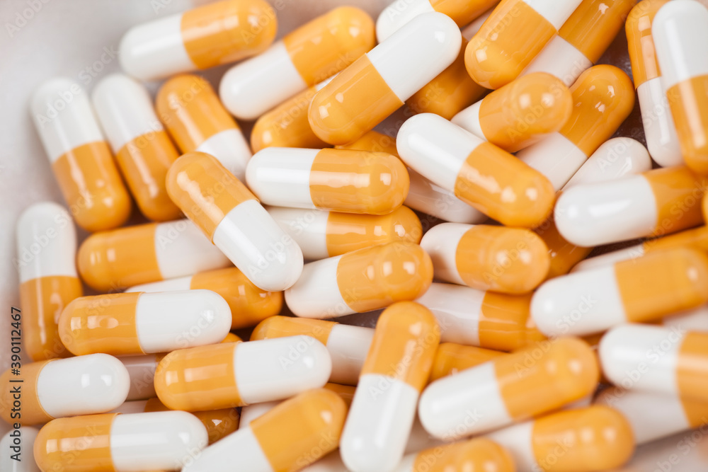 Close up of orange and white capsules/vitamins/pills. Selective focus on object. Close up of orange and white capsules/vitamins/pills. Selective focus on object.