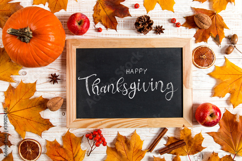 Thanksgiving greetings. Dry yellow leaves, pumpkins, berries, apples and frame on a white background, top view. Kaligraphic capital inscription.