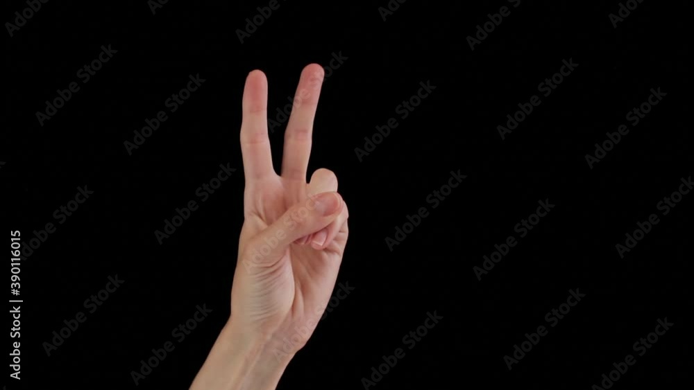 Female hand demonstrates victory sign on black background Female hand demonstrates victory sign on black background