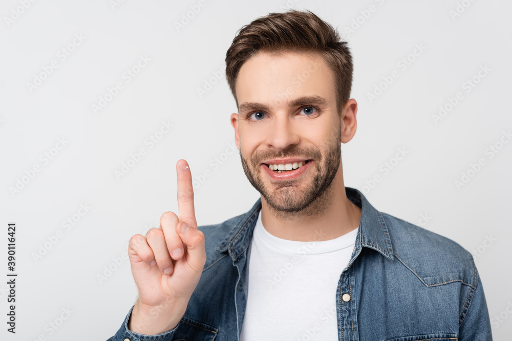 Smiling man looking at camera while holding contact lens isolated on grey Smiling man looking at camera while holding contact lens isolated on grey