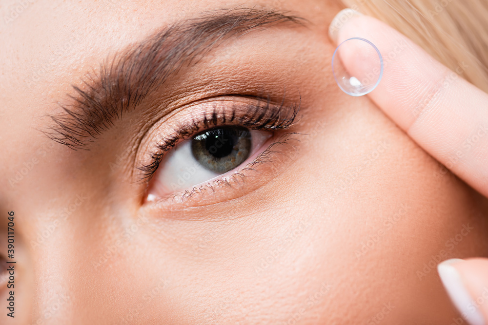 Obraz premium Close up view of woman holding contact lens near eye