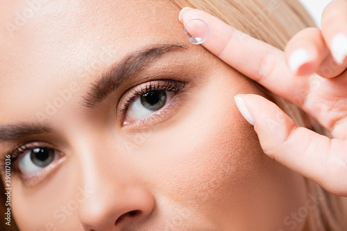 Cropped view of woman looking at camera while holding contact lens isolated on white