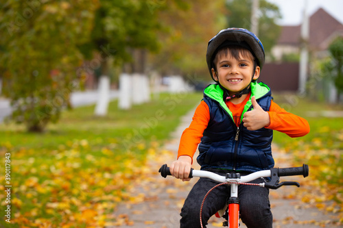 Boy in the autumn park on a bike. A small child shows the class. Active healthy outdoor sports. Photo with empty space