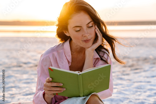 Bild auf Leinwand Smiling beautiful young woman reading a book
