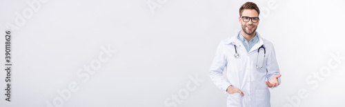 Front view of cheerful ophthalmologist with hand in pocket, wearing eyeglasses and gesturing on grey background, banner © LIGHTFIELD STUDIOS