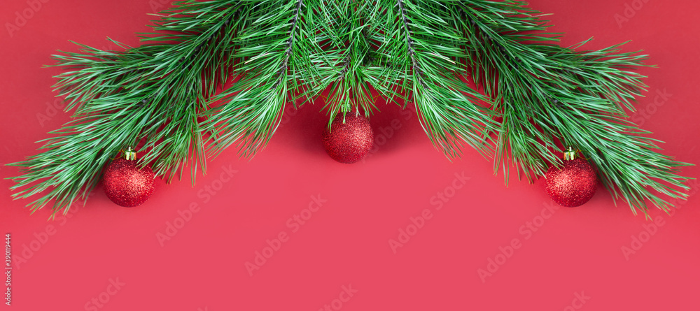 Christmas tree branches with red glittering balls on red background with copy space Christmas tree branches with red glittering balls on red background with copy space