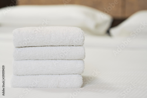 White clean towels stacked on bed in bedroom
