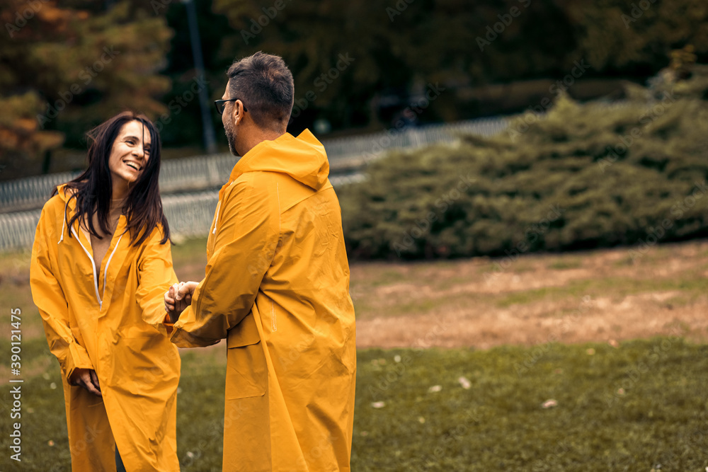 Mid adult couple in raincoat enjoying together and having fun in city park after rain. Mid adult couple in raincoat enjoying together and having fun in city park after rain.