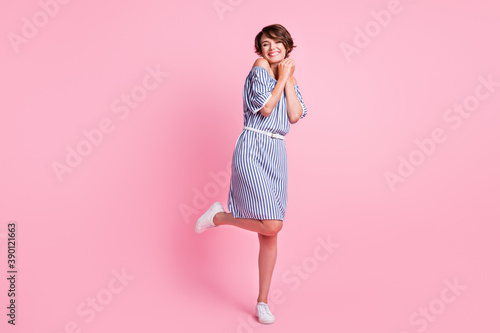 Photo portrait full body view of cute girl with hands together standing on one leg isolated on pastel pink colored background