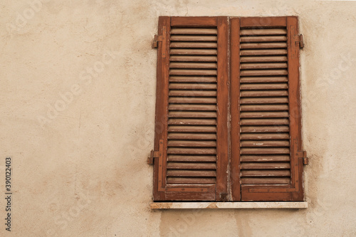 Bright wall with old window and closed brown wooden shutters, space for text, ideal for background or template