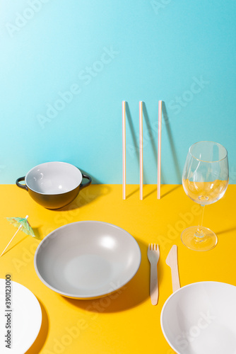 Various plates, utensils, a glass and umbrella decoration on a colorful table