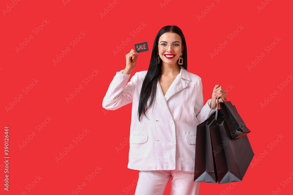 Beautiful young woman with shopping bags and credit card on color background. Black Friday sale