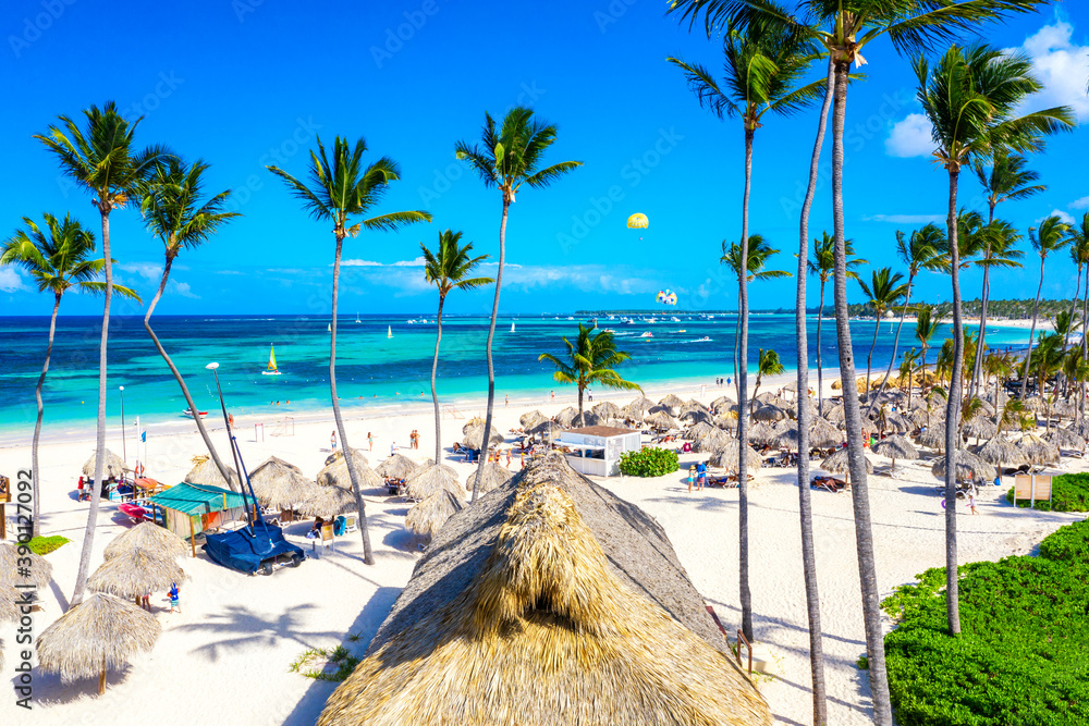 Beach vacation. Aerial drone view of tropical white sandy Bavaro beach in Punta Cana, Dominican Republic. Amazing landscape with palms, umbrellas and turquoise water of atlantic ocean - obrazy, fototapety, plakaty 