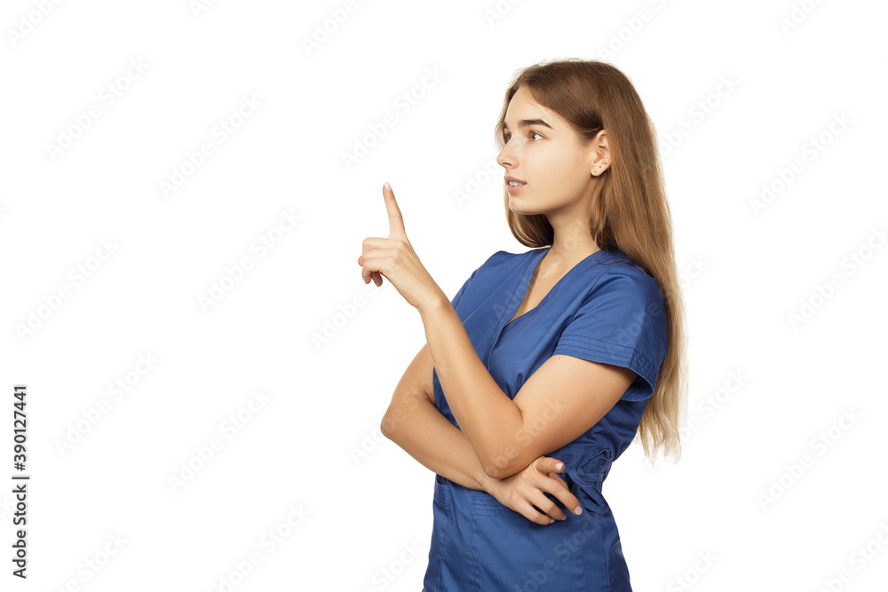Young beautiful female doctor in a blue surgical gown shows a finger to the side isolated on a white background. Copspace Young beautiful female doctor in a blue surgical gown shows a finger to the side isolated on a white background. Copspace