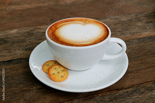 Closeup a cup of cappuccino coffee with a pair of crackers isolated on wooden table