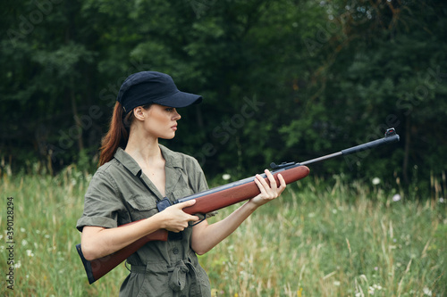 Woman soldier Holds weapons in side view green leaves 