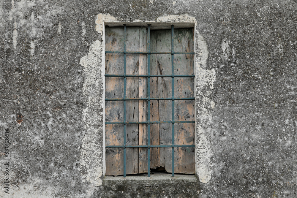 cracked and dirty house facade with old window with wood and steel elements, the shutter is closed and space for text cracked and dirty house facade with old window with wood and steel elements, the shutter is closed and space for text